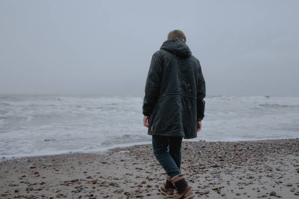 istock a guy in a black warm jacket walks along the seashore, stands sepina 1363872593