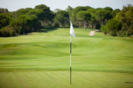 An idyllic golf green flag on a perfect, clear morning.