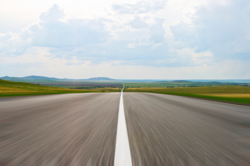 Highway leaving in the sky with green grass on roadside