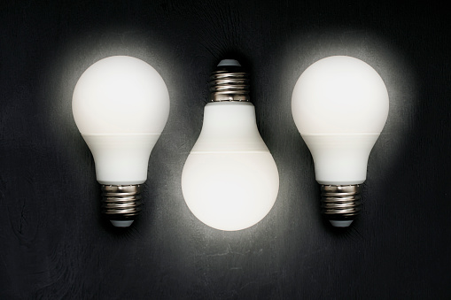 three energy saving light bulbs on a black background