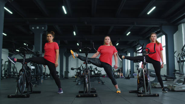 gruppo caucasico sano di donne che esercitano lo stretching su una cyclette in palestra - spinning health club instructor gym foto e immagini stock