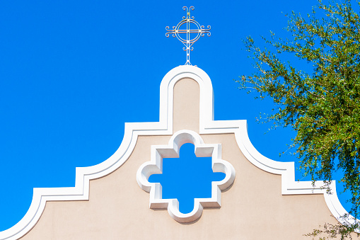 A stylized metal cross on top of a Spanish influenced church in St. Augustine, Florida