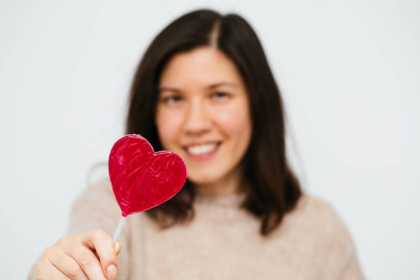 istock Beautiful Woman Holding Heart Shape Candy 1363884295