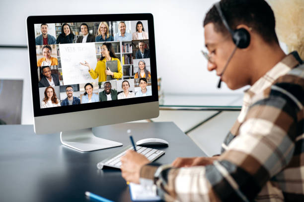 successful mixed race clever male student learning distantly. at laptop screen female teacher and students. teacher conducts online lecture, male student with headset takes notes. video call - simulator bildbanksfoton och bilder