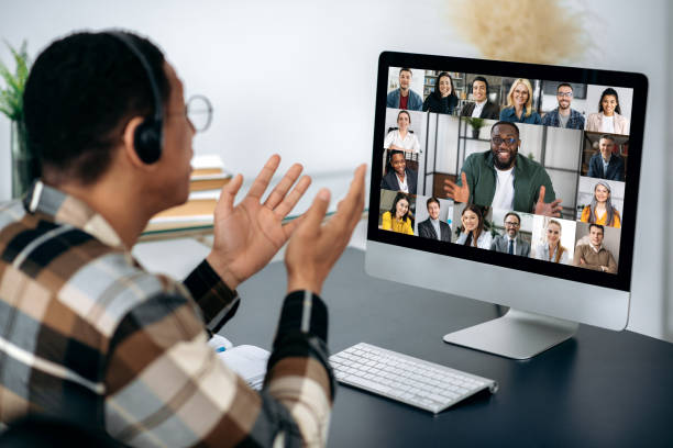 istock Video call, online conference. Over shoulder view of mixed race man, on computer screen with multinational group of successful business people, virtual business meeting, telecommunication concept 1363885040