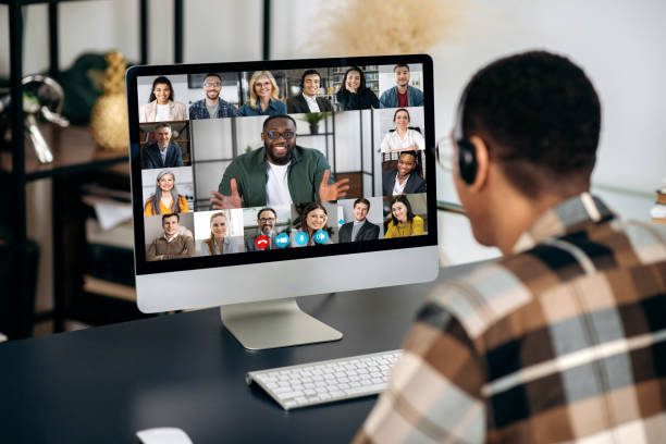 istock Online video communication. Over shoulder view of mixed race man, on computer screen with multinational group of successful business people, virtual business meeting, telecommunication concept 1363885043