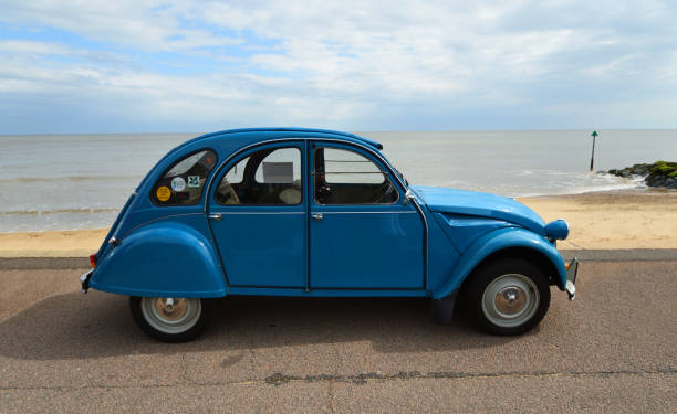 classic blue citroen 2cv  deux chevaux parked on seafront promenade. - citroën 2cv stockfoto's en -beelden