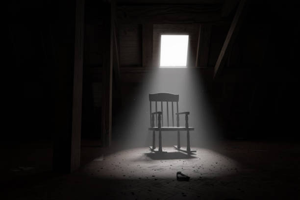 3d rendering of old rocking chair illuminated by light ray at dark attic. Concept age and past stock photo