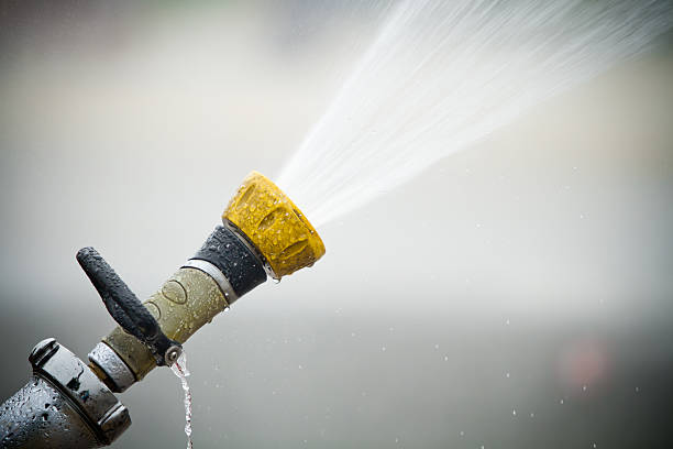Fire hose shooting water out Fixed fire hose spraying water with blurred background. water hose stock pictures, royalty-free photos & images