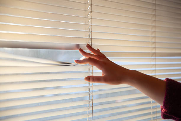istock Woman's hand taking a peak through the window blinds. 1363889802