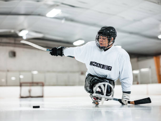 mulher latina com deficiência madura jogando hóquei de trenó - ice hockey ice ice skating sport - fotografias e filmes do acervo