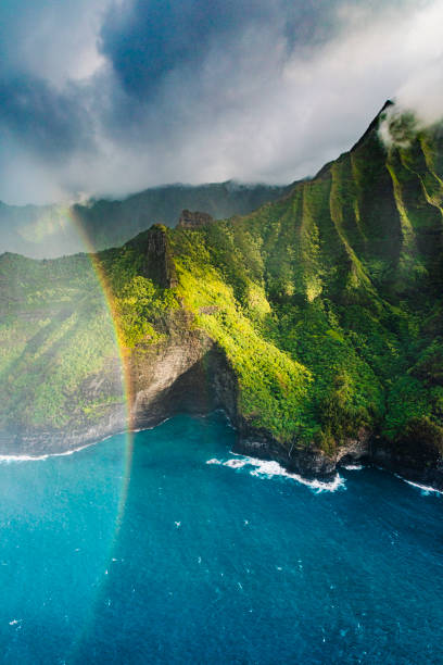 hermosa vista aérea de la costa de na pali encontrándose con agua azul brillante detrás de un arco iris - exotic location fotografías e imágenes de stock