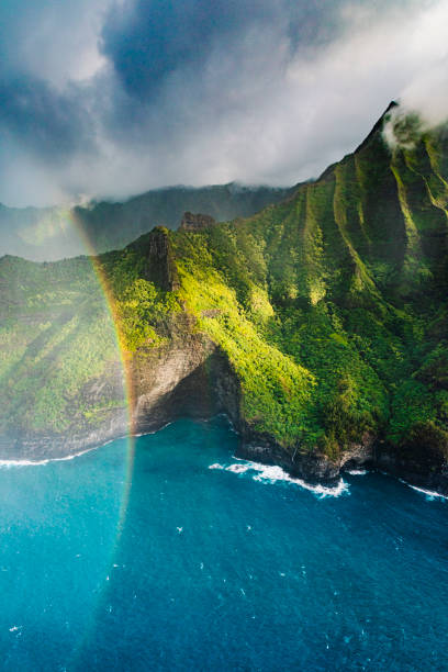magnifique vue aérienne de la côte de na pali rencontrant de l’eau bleu vif derrière un arc-en-ciel - hawaii islands mountain kauai sea photos et images de collection