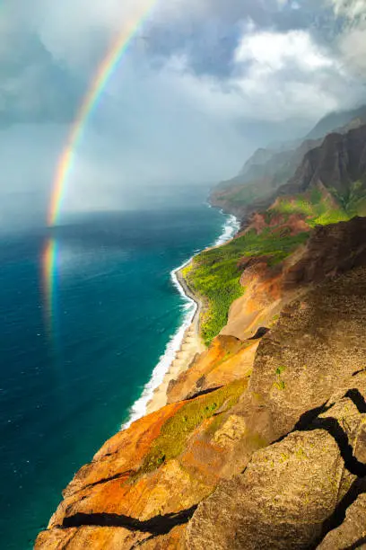 Bright rainbow meeting the ocean on Hawaiian coastline