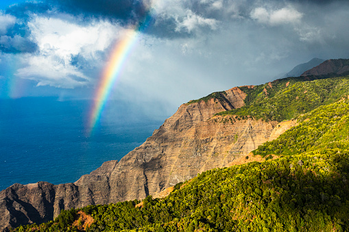 Bright, vibrant rainbow shining above rocky coastline