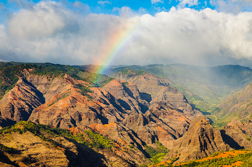 Bright rainbow over canyon on Kauai island