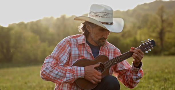 istock Cowboy in nature playing the guitar at sunset. Springtime stayca 1363894305