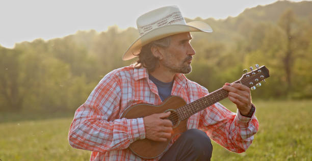istock Cowboy in nature playing the guitar at sunset. Springtime stayca 1363894306