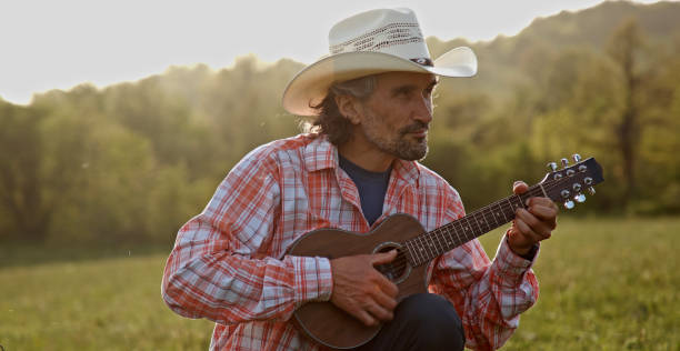 istock Cowboy in nature playing the guitar at sunset. Springtime stayca 1363894308