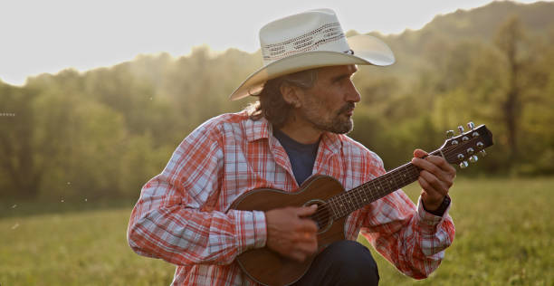 istock Cowboy in nature playing the guitar at sunset. Springtime stayca 1363894309