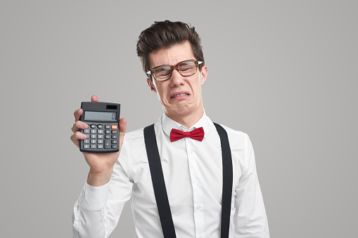 Comic crying male bookkeeper grimacing and showing calculator with number zero on gray background in studio