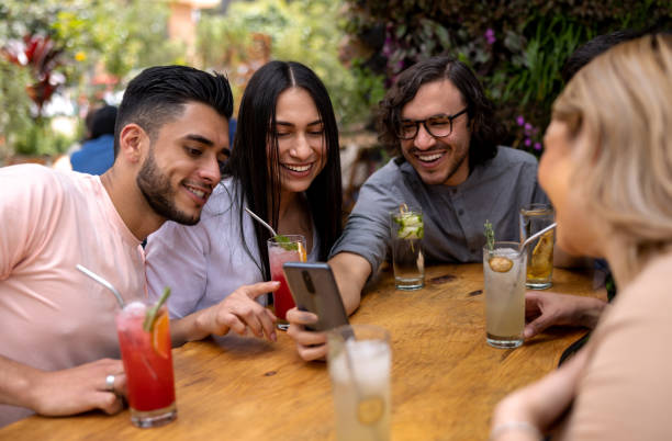 istock Happy friends having drinks at a restaurant while looking at something funny on social media 1363895244
