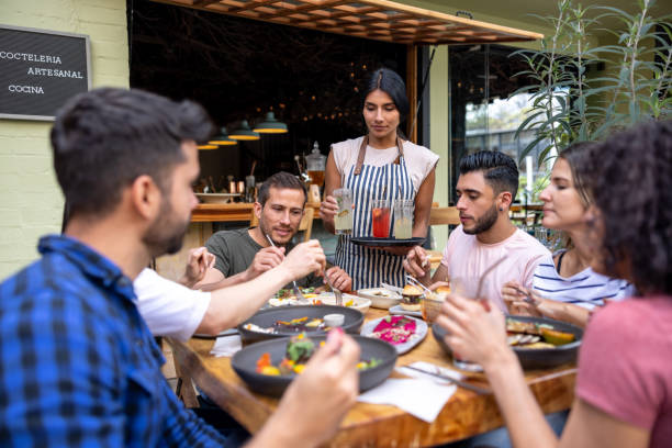 istock Waitress serving drinks to a group of friends at a restaurant 1363895281