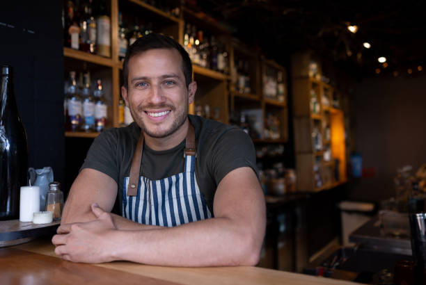 Portrait of a happy Latin American bartender working at the bar and looking at the camera smiling