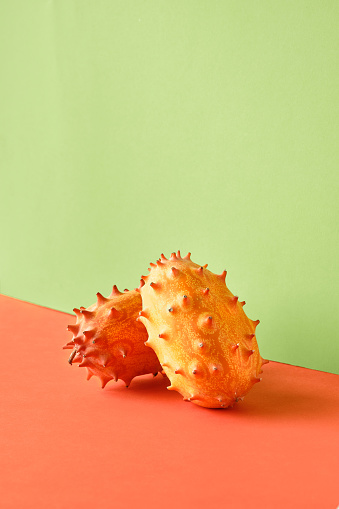 Dragon fruit, pitahaya, close-up on two color paper background. Vibrant orange and mint green vibrant colors. Closeup on two spiky cactus fruits.