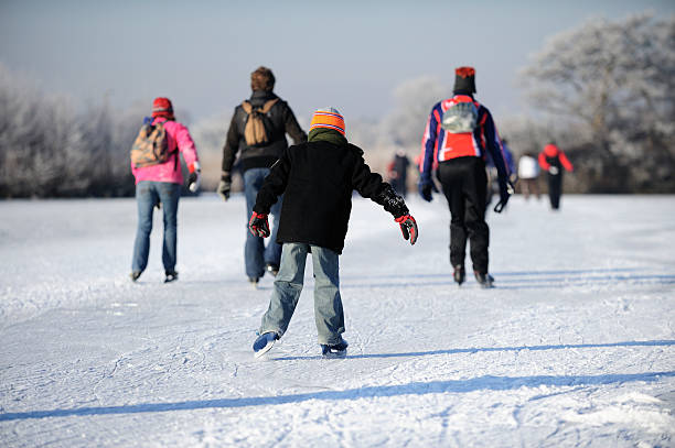 A first person shot of person's feet in ice skates standing on ice.