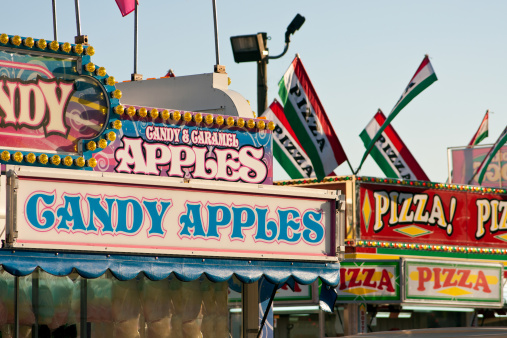 Candy apples and pizza are some of the fast food options on display at a county fair.