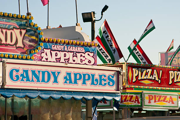 Carnival Candy Apple and Pizza Stands Candy apples and pizza are some of the fast food options on display at a county fair. midway fair stock pictures, royalty-free photos & images