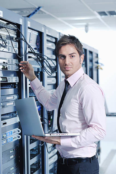 istock Businessman with a laptop working in a network server room 136389873