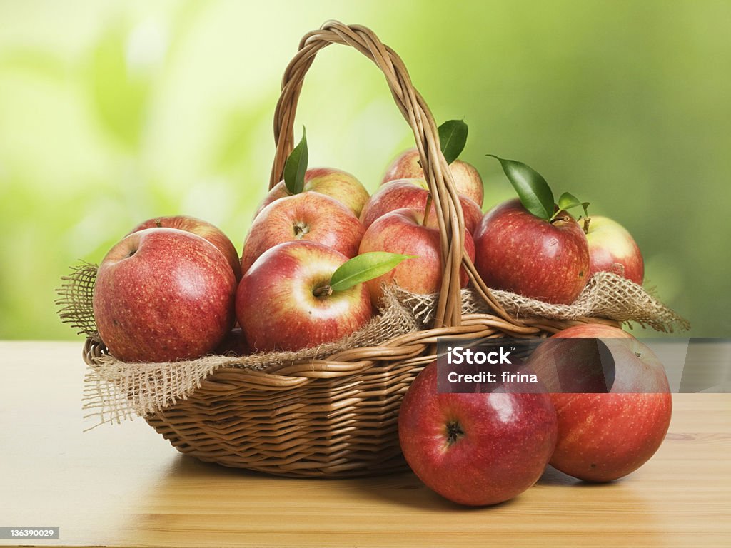 Jonagold Apples in a Basket Jonagold apples in a basket on wooden table against garden background Apple - Fruit Stock Photo