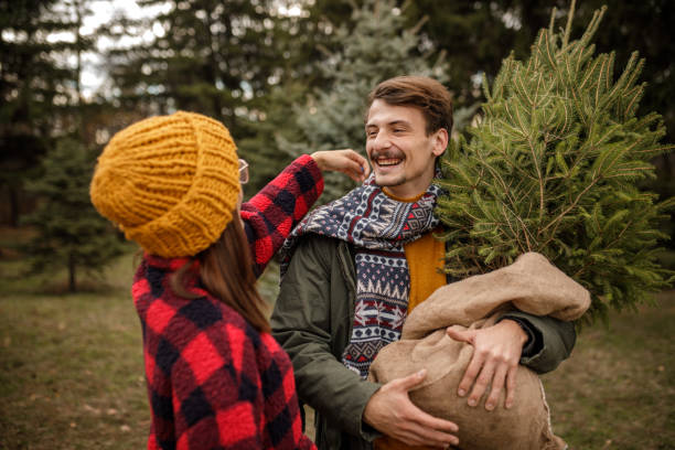 istock Young couple having fun time together while carrying their new Christmas tree home 1363903997