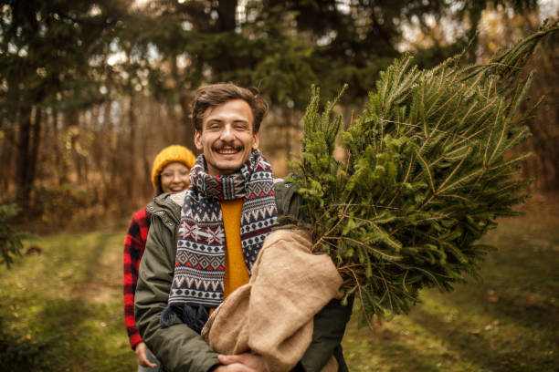 istock Happy couple carrying their Christmas tree 1363904000