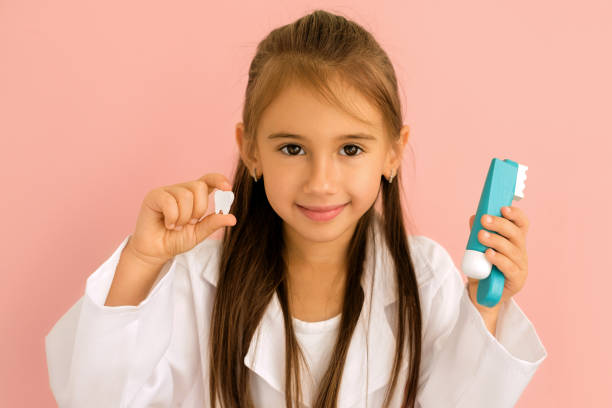 istock Small dentist holds a model of a tooth and a toothbrush with toothpaste 1363904874