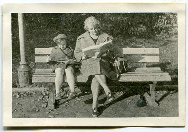 vintage photo of mother and daughter reading in park - lezen fotos stockfoto's en -beelden