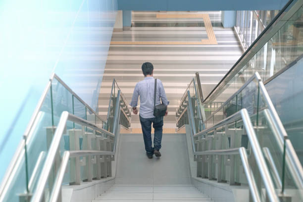 hombre bajando las escaleras de un edificio moderno - stair rail fotografías e imágenes de stock