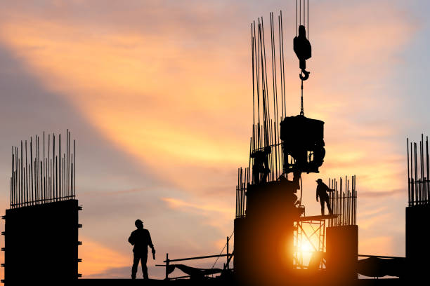istock Silhouette of Engineer and worker checking project at building site background, construction site at sunset in evening time 1363931480