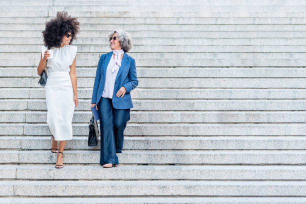 Rear view of business woman walking up steps in city - full length