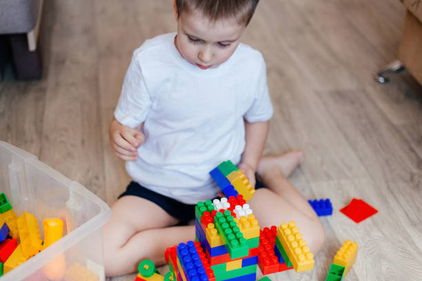 istock Boy in a white T-shirt playing with lots of colorful plastic blocks constructor 1363934615