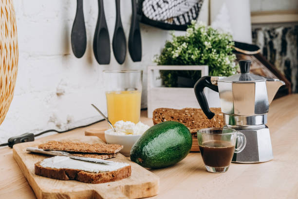 desayuno alimento aguacate queso blando huevo de pepino verde, pan multigrano y pan crujiente. haciendo tostadas de aguacate o sándwich. taza de café expreso y olla moka. - avocado lemon snack cracker fotografías e imágenes de stock