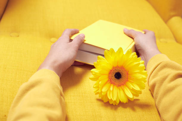 istock A yellow chair with a book in hands in which a flower is placed. 1363939921
