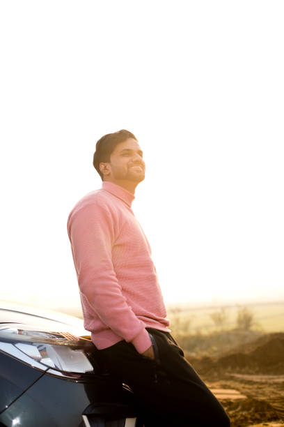 istock Happy young man leaning on car and admiring view 1363943139