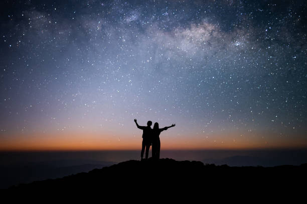 silhouette eines liebespaares beobachtete den stern und die milchstraße allein auf dem gipfel des berges. er reiste gerne und war erfolgreich, als er den gipfel erreichte. - milky way star galaxy space stock-fotos und bilder