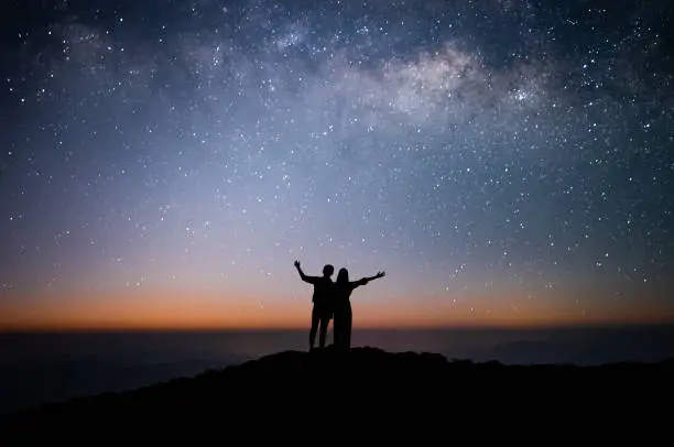 Photo of Silhouette of couple of lovers watched the star and milky way alone on top of the mountain. He enjoyed traveling and was successful when he reached the summit