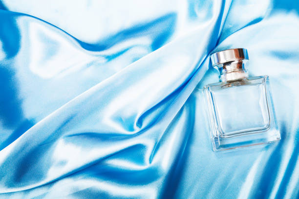 istock Elegant cosmetic advertising. Perfume bottle on light blue silk folded fabric background. Scent fragrance cosmetic beauty product. Flat lay. 1363946871