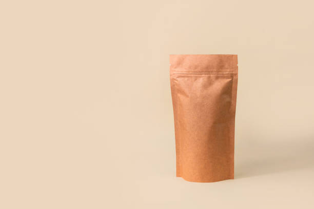 istock Pouch bag mockup neutral beige background monochrome. Merchandise packaging. Blank brown kraft paper pack demonstration. 1363947267