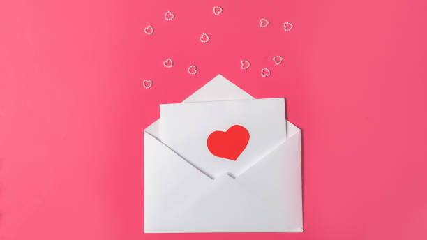istock Red paper envelope with blank white note mockup inside on pink background. Flat lay, top view. Romantic love letter for Valentine's day concept. Space for text 1363947991